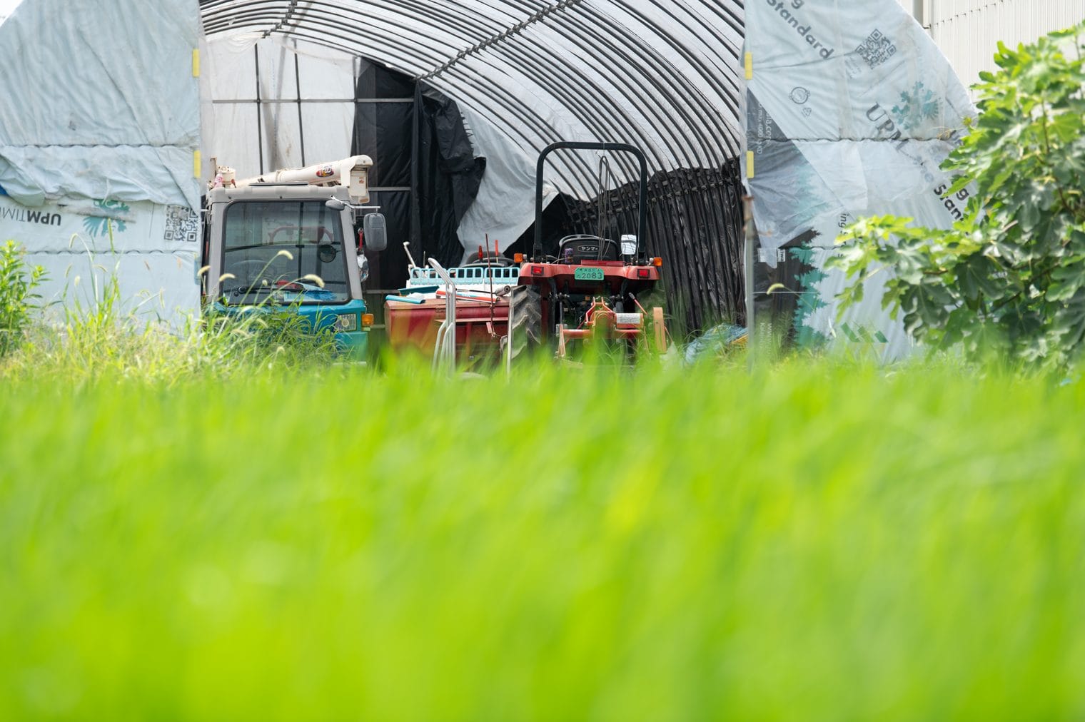 ハウスに置かれたトラクターと作業車